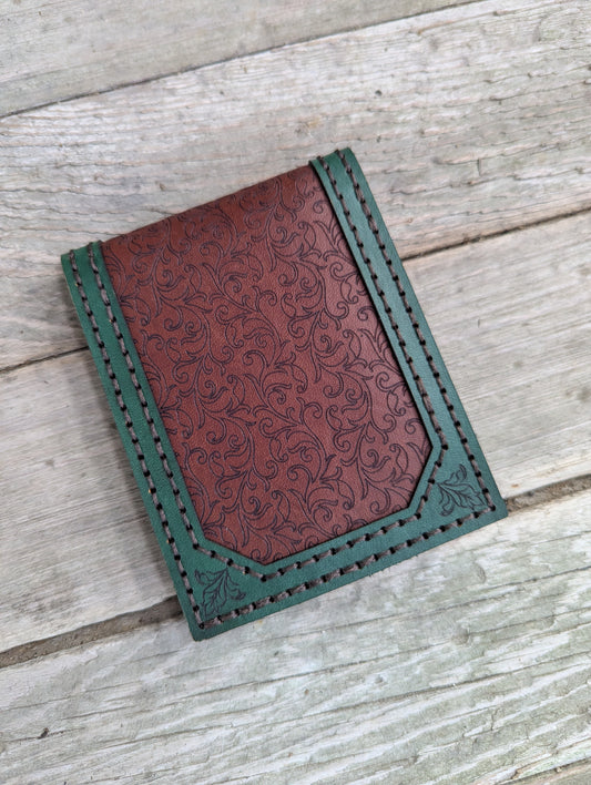 Brown leather wallet with green border on a wooden surface
