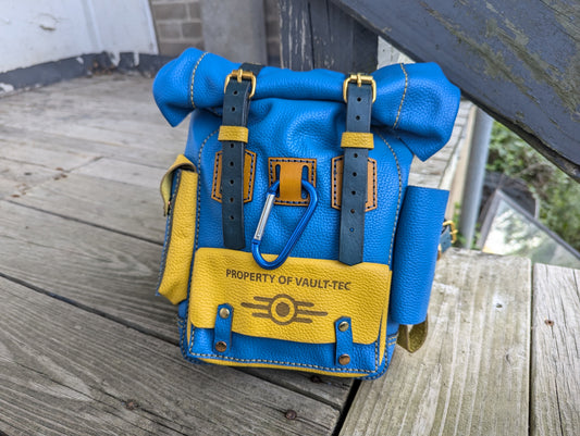 Handcrafted full grain leather mini roll top bag in blue and yellow vault colors with dual buckle straps and carabiner